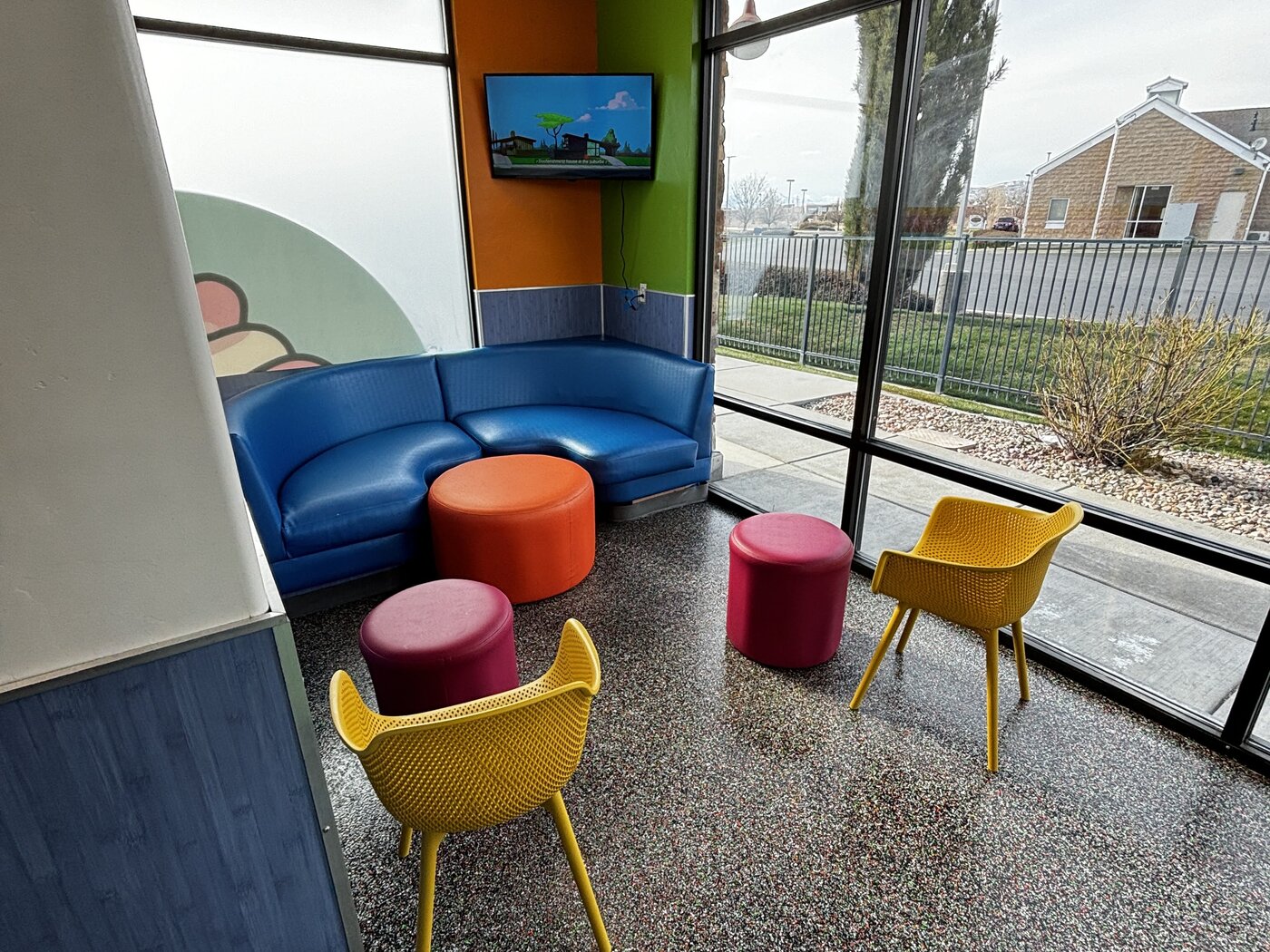 American Fork lounge with blue couch, yellow chairs, and a TV mounted in the corner