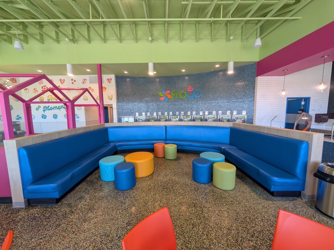 Spanish Fork wraparound blue booth with colorful poof seats facing the froyo machine wall